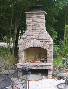 an outdoor fireplace with chairs around it