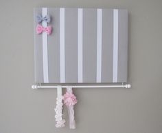 a gray and white striped wall hanging with pink bows