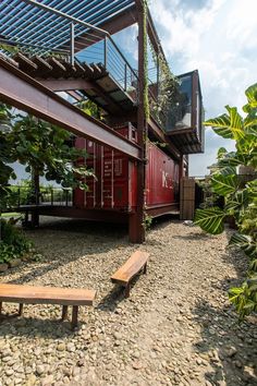 a wooden bench sitting in front of a red shipping container on the side of a building