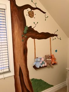 a child's bedroom with a tree painted on the wall and stuffed animals hanging from it