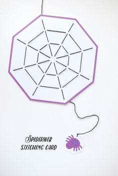 an origami spiderweb sitting on top of a white card with purple string