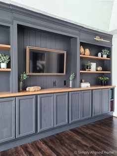 an entertainment center with gray cabinets and wood flooring