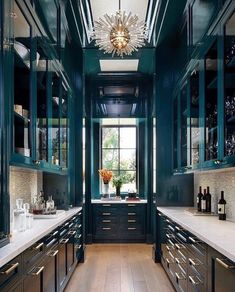 a kitchen with dark green cabinets and white counter tops, along with wooden flooring