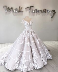 a white wedding dress on display in front of a sign that says mak timg