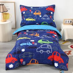 a child's bed with cars on it and blue comforter set in the corner