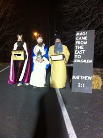 three people dressed in costumes standing next to a sign