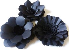 three black paper flowers on a white surface