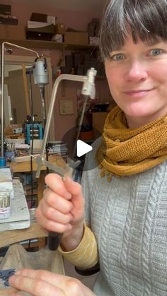 a woman is holding scissors in her hand and smiling at the camera while she works on something