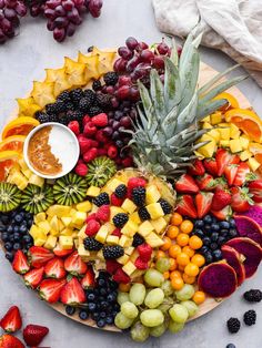 a platter filled with fruit, berries, pineapples, and other fruits