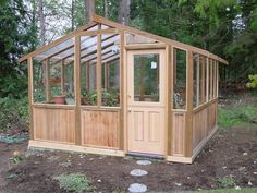 a small wooden greenhouse in the middle of some dirt