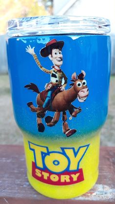 the toy story tumbler cup is sitting on top of a wooden table with an image of woody riding a horse