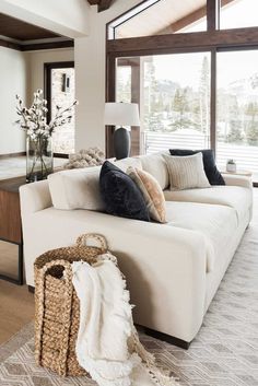 a living room filled with white furniture and lots of pillows on top of the couch