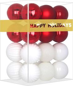 red and white christmas balls in a box with a happy holidays sign on it's side