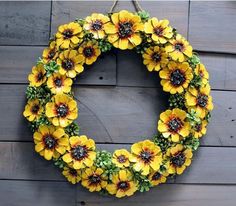 a wreath with yellow flowers hanging on a wooden wall