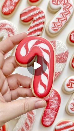 someone is holding a candy cane cookie in front of some cookies that are decorated with icing