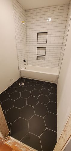 an empty bathroom with black and white tile