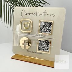 a white and gold display with qr - code magnets in front of a palm tree