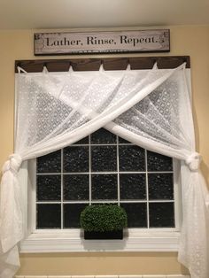 a window with white curtains and a potted plant