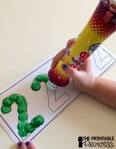 a child's hand holding a tube with the letter j on it