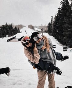 two people standing in the snow with skis on and one person wearing goggles