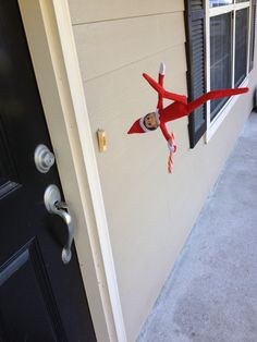 an elf is hanging on the side of a door with a candy cane in his hand