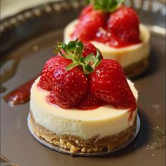 two cheesecakes with strawberries on top are sitting on a metal platter