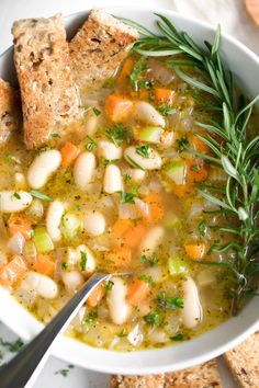 a white bowl filled with soup next to crackers and bread on top of a table