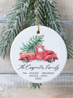 an ornament hanging from a christmas tree with a red truck and pine branches