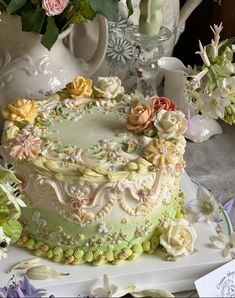 a decorated cake sitting on top of a white plate next to flowers and vases