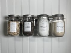 five jars with labels on them are lined up against the wall, each containing different types of spices