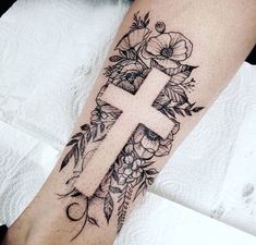 a cross with flowers and leaves on the arm