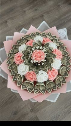 an arrangement of money and flowers on top of each other in a bouquet with pink paper