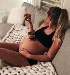 a pregnant woman sitting on top of a couch