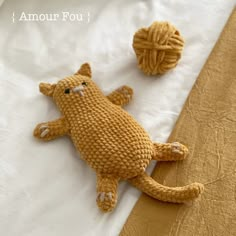 two crocheted animals laying on top of a bed next to a ball of yarn