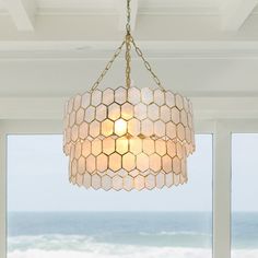 a chandelier hanging from the ceiling in front of a window overlooking the ocean