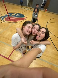 three girls hugging each other on a basketball court