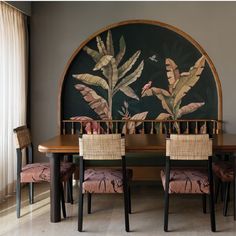 a dining room table with chairs and a painting on the wall in the back ground