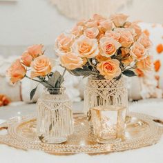 two vases filled with flowers sitting on top of a gold tablecloth covered tray