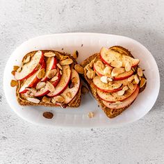 two slices of toast with apples and almonds on it sitting on a white plate