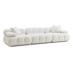 a white couch with pillows on it and one arm facing the camera, in front of a