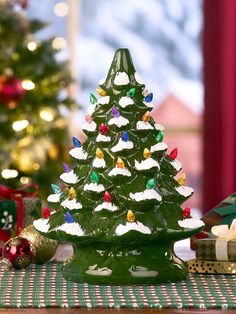 a green ceramic christmas tree sitting on top of a table next to a small gift box