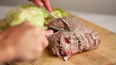 a person cutting up some meat with a knife and fork on top of a wooden cutting board