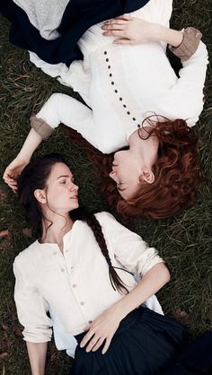 two young women laying on the ground with their heads touching each other's shoulders