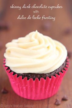 a chocolate cupcake with white frosting on a wooden table