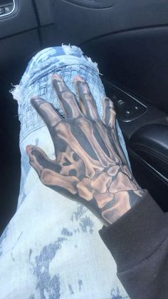 a person's hand is covered in black and grey ink while sitting in the driver's seat