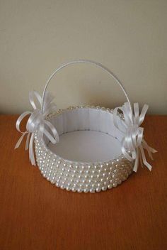 a white basket with pearls and bows on a table