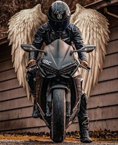 a man riding on the back of a motorcycle next to an angel wings wallpaper