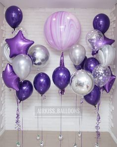 purple and silver balloons are hanging from the wall