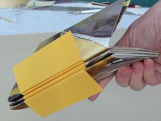 a person holding scissors in their hand with yellow paper on top of the other pieces