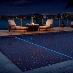 an outdoor swimming pool with blue leds and lounge chairs around it at night time